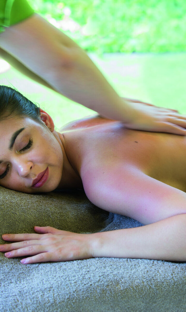 Eine Frau liegt entspannt auf einer Liege und erhält eine Rückenmassage.