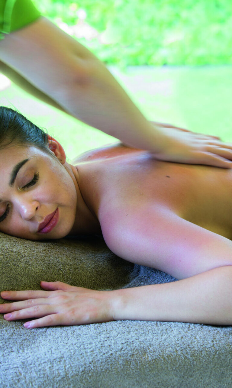 Eine Frau liegt entspannt auf einer Liege und erhält eine Rückenmassage.
