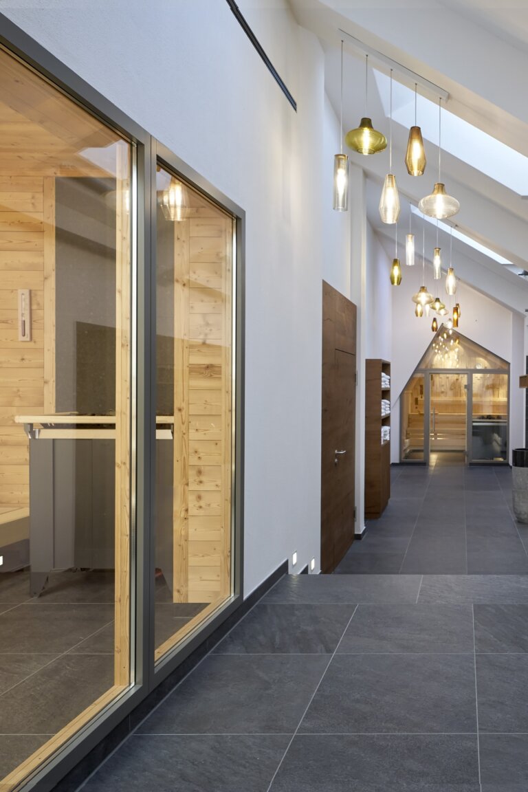 Ein moderner Saunabereich mit Sauna, Glasfronten und Hängelampen im Wellnesshotel Traube Tonbach.
