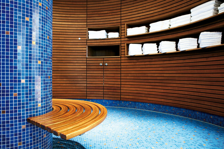 Ein moderner Wellnessbereich mit Holzwänden, blauer Mosaiksäule und Handtuchregalen im Hotel Traube Tonbach.