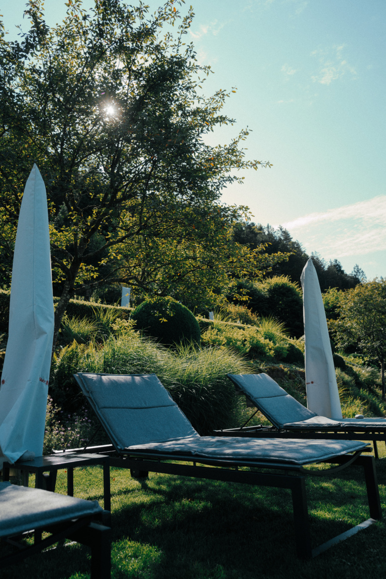 Liegestühle im Garten des Hotel Traube Tonbach, Sonnenschirme und grüne Umgebung mit Waldkulisse.