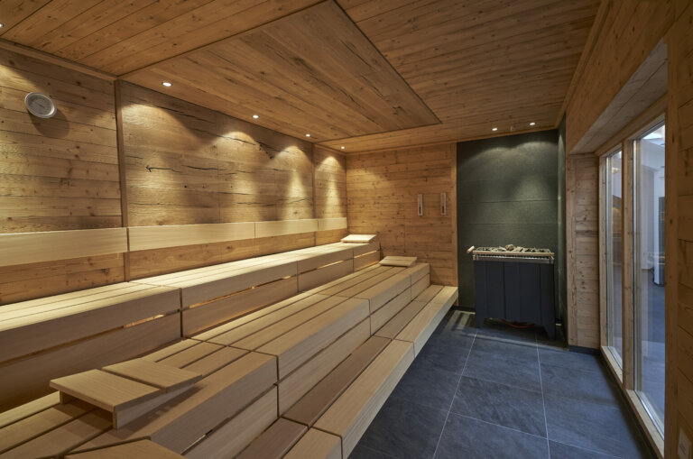 Eine Holzsauna mit modernen Sitzbänken und Saunaofen in einem Hotel mit Wellness im Schwarzwald.
