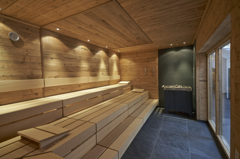 Eine Holzsauna mit modernen Sitzbänken und Saunaofen in einem Hotel mit Wellness im Schwarzwald.