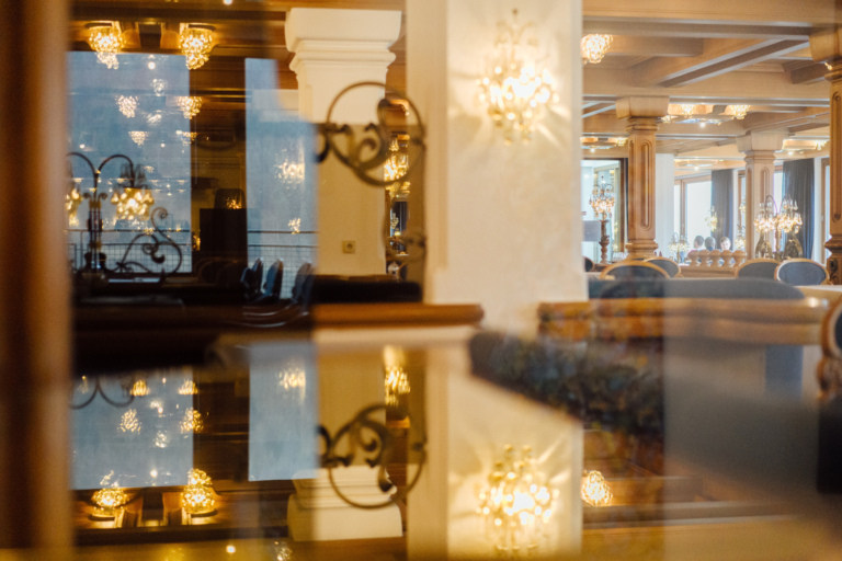 Ein eleganter Foyer eines Luxushotels mit reflektierenden Oberflächen, Kronleuchtern, stilvollen Möbeln und einer weichen Beleuchtung in warmen Farben.