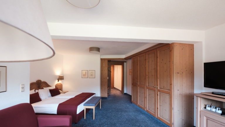 Ein Hotelzimmer mit einem Doppelbett, Kleiderschrank, Fernseher und Sitzbereich.