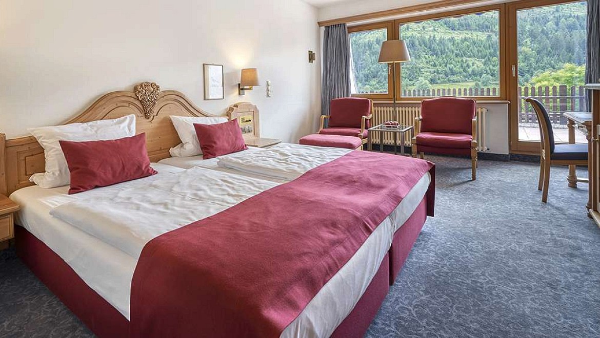 Minimalistisch gestaltetes Hotelzimmer im Schwarzwald mit grauen Sofamöbeln und Balkon.