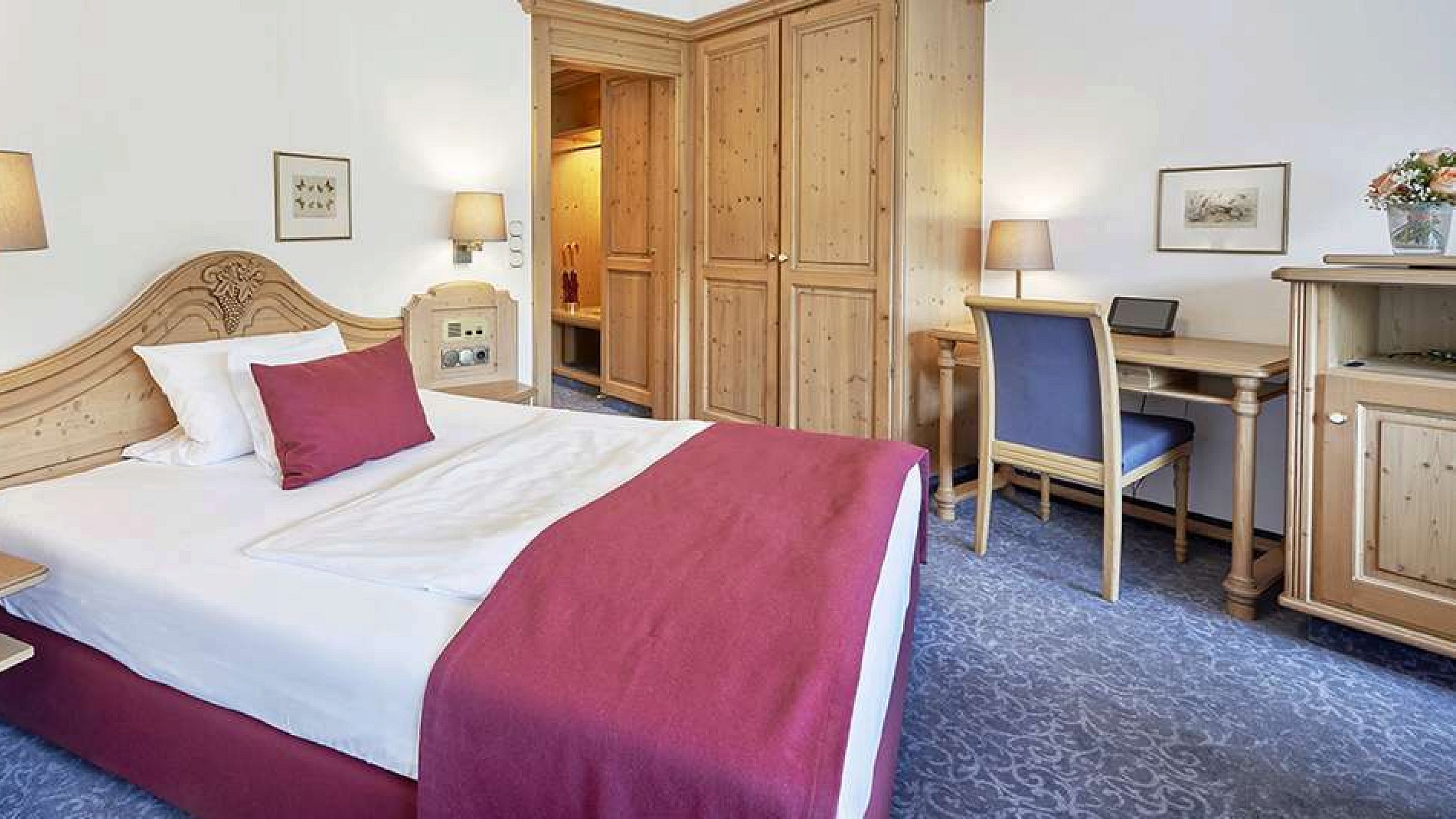 Hotelzimmer im Schwarzwald mit gemütlichem Bett, Kleiderschrank und Schreibtisch.