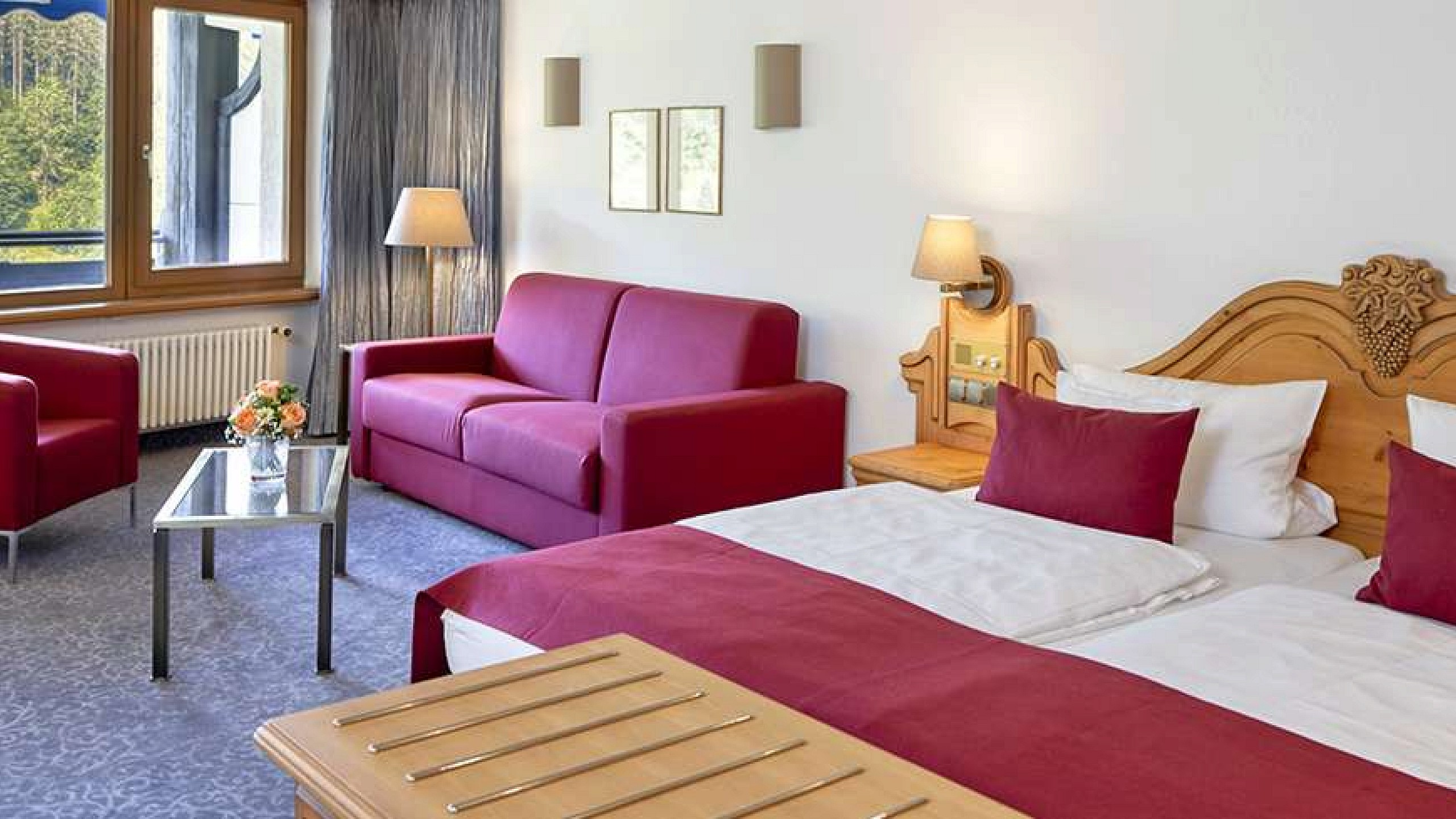 Hell eingerichtetes Hotelzimmer im Schwarzwald mit Doppelbett und Sitzgelegenheiten.