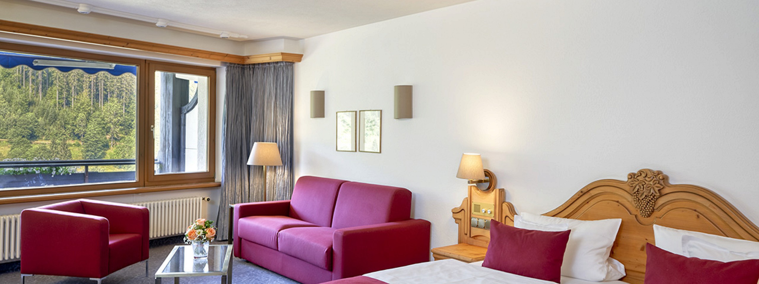 Hell eingerichtetes Hotelzimmer im Schwarzwald mit Doppelbett und Sitzgelegenheiten.