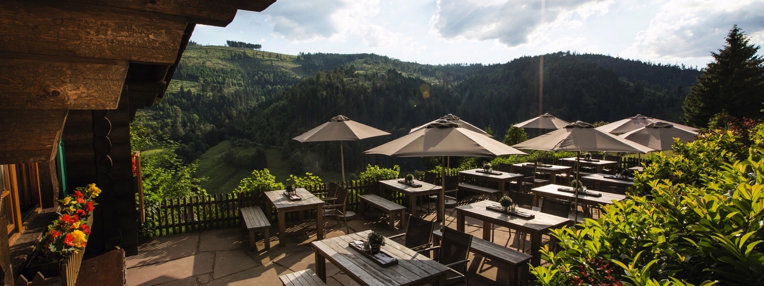 Terrasse der Blockhütte mit Sonnenschirmen im Hotel mit Arrangements im Schwarzwald.