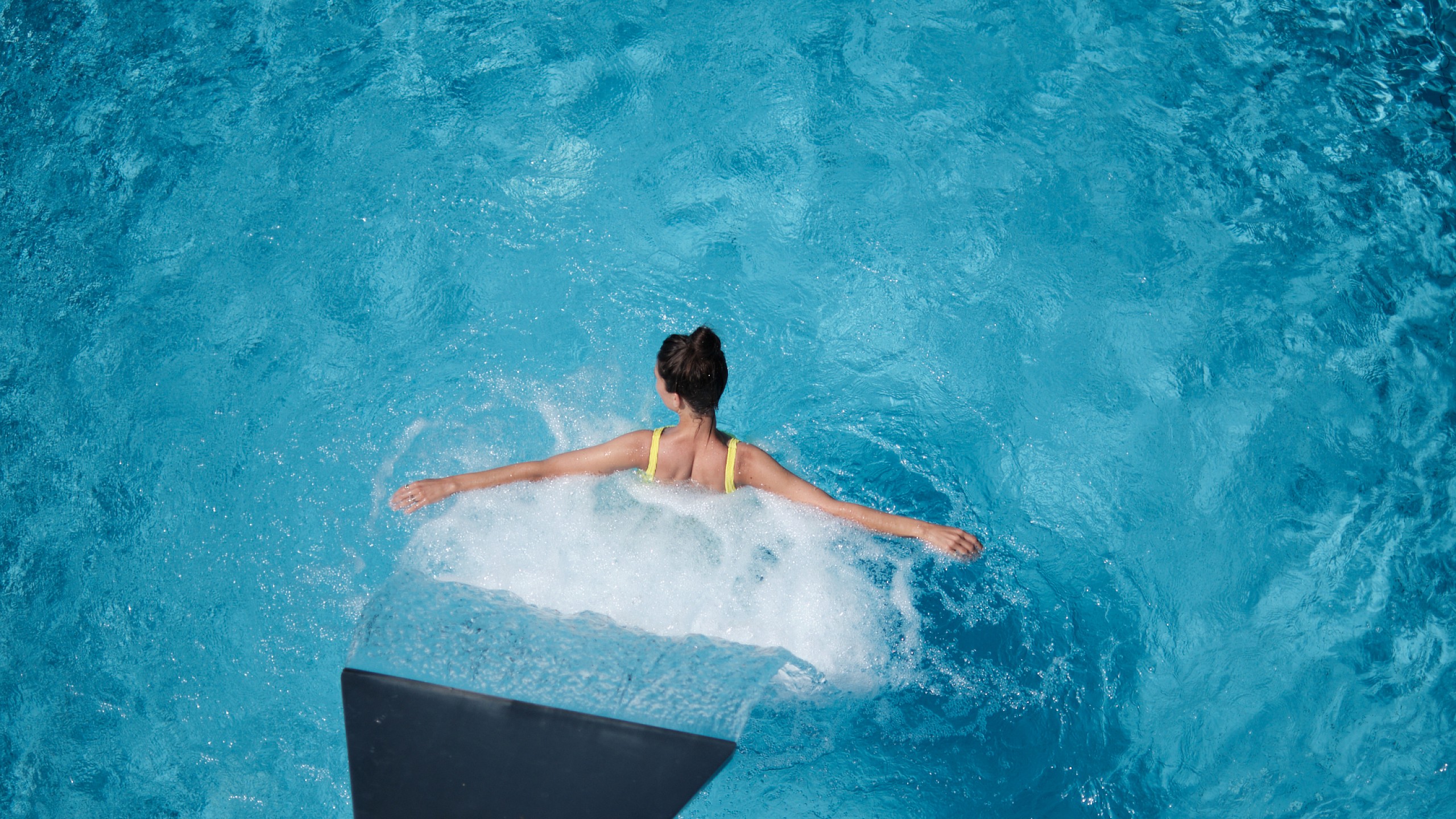 Eine junge Frau badet im Pool des 5 Sterne Superior Hotels im Schwarzwald.