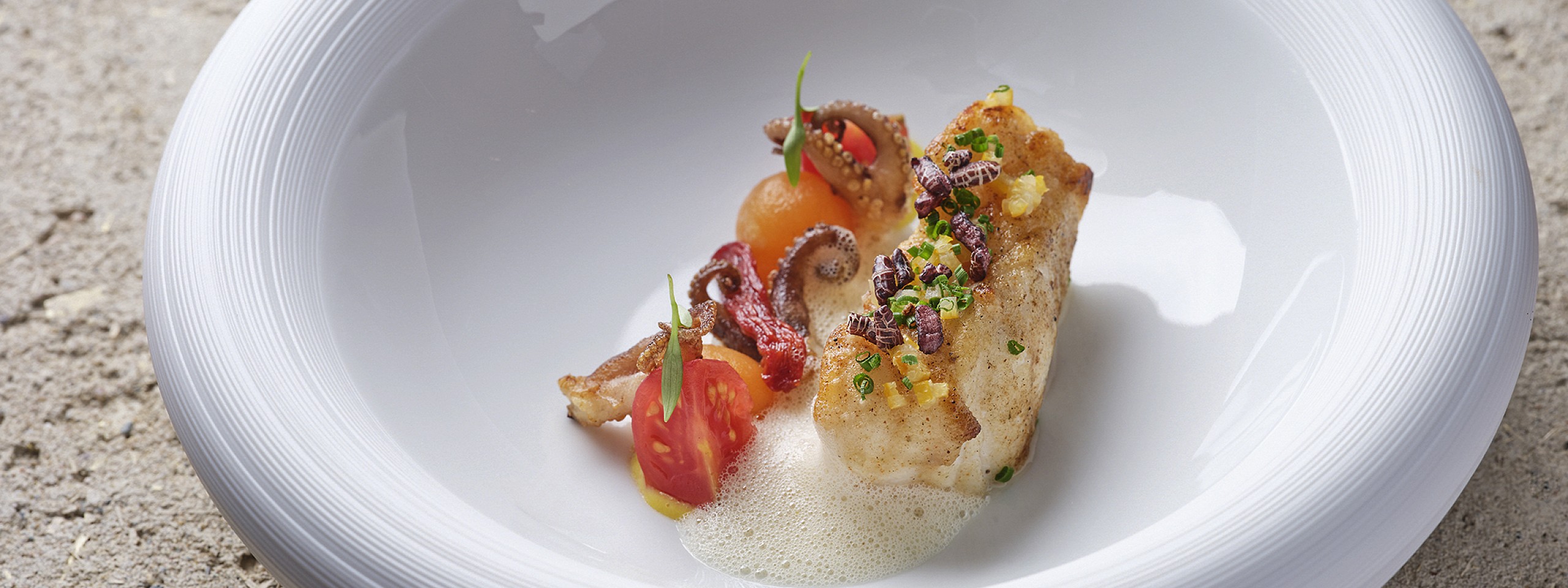 Leckeres Fischgericht auf tiefem weißen Teller im Sterne Restaurant im Schwarzwald.