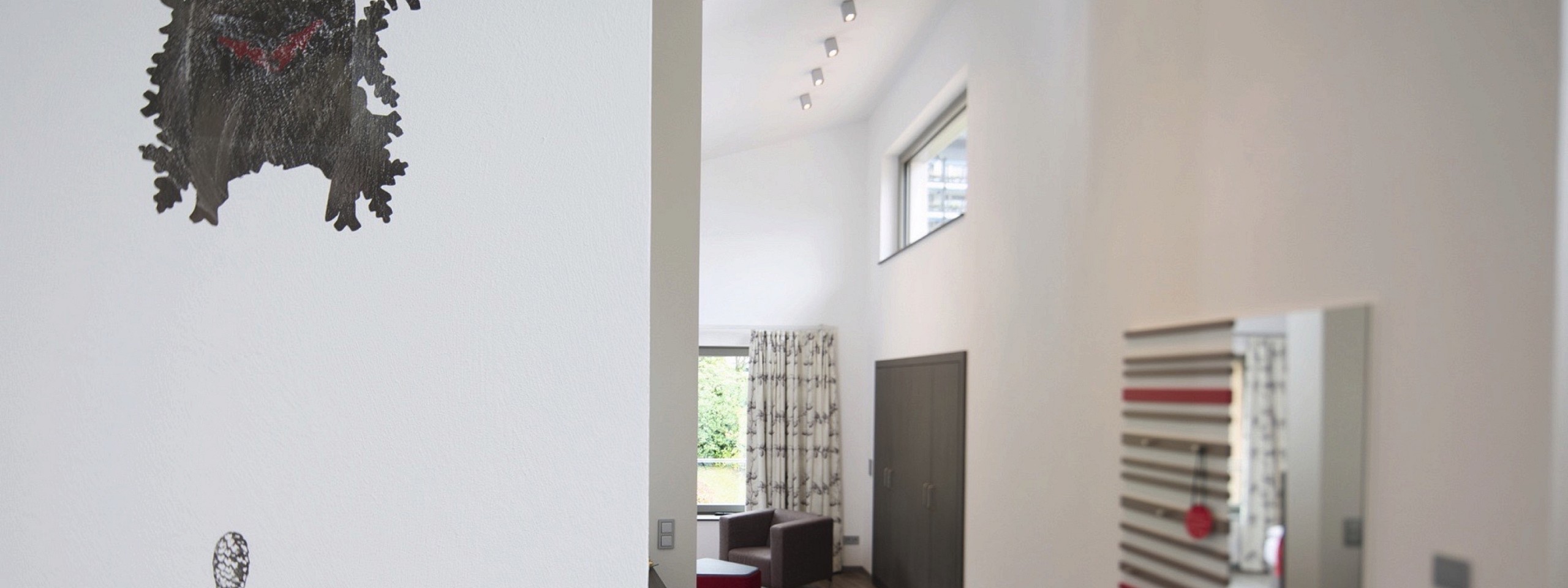 Flurbereich eines der Hotelzimmer im Schwarzwald mit einer gemalten Kuckucksuhr an der Wand.