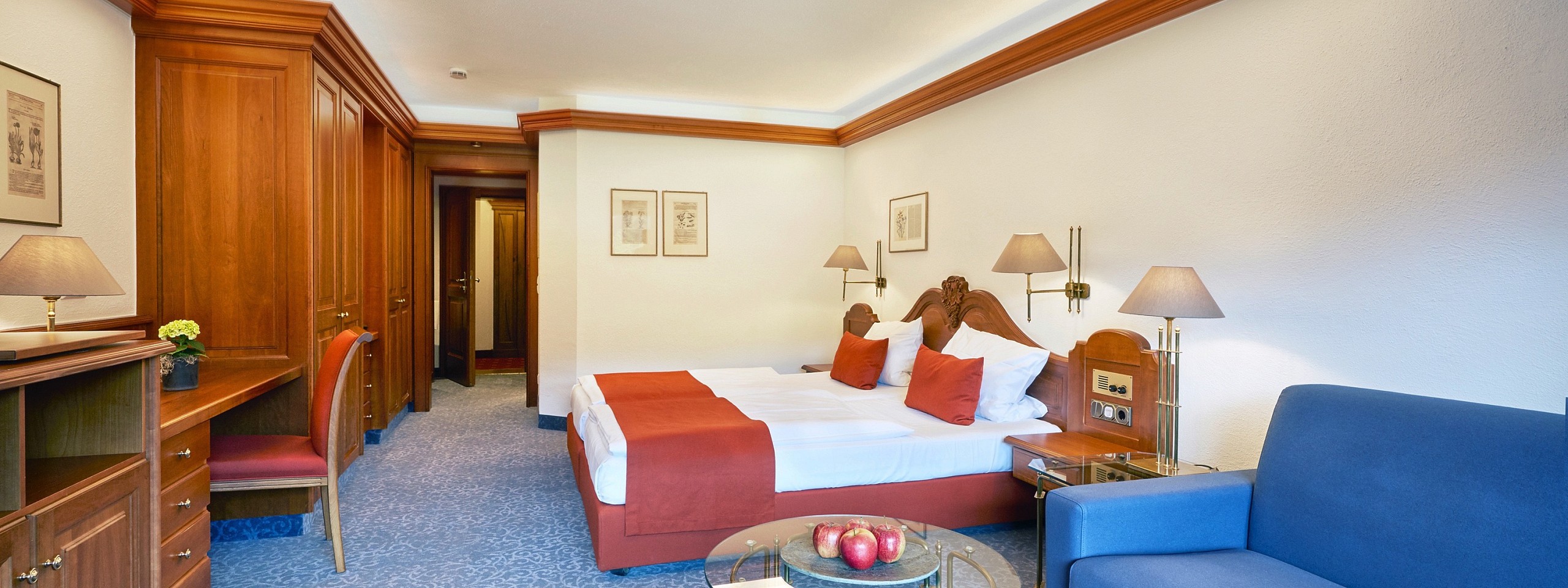 Einladend eingerichtetes Hotelzimmer im Schwarzwald mit blauen und roten Akzenten.