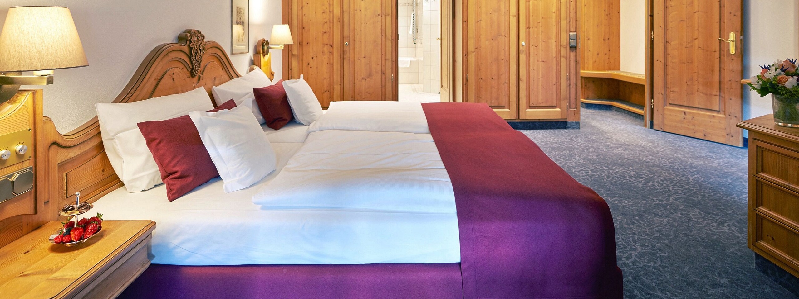 Doppelbett umgeben von hölzernen Möbeln im Hotelzimmer im Schwarzwald.