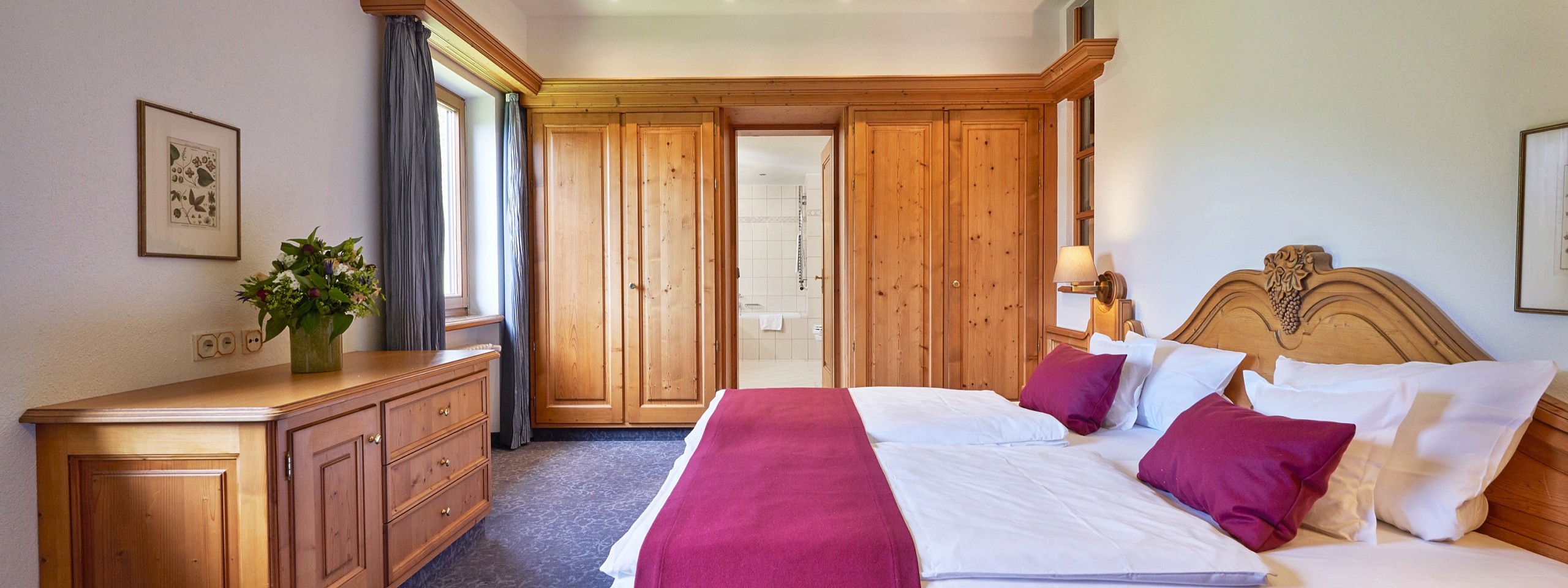 Doppelbett mit einer großen Kommode am Fußende und Blick ins Badezimmer im Hotelzimmer im Schwarzwald.